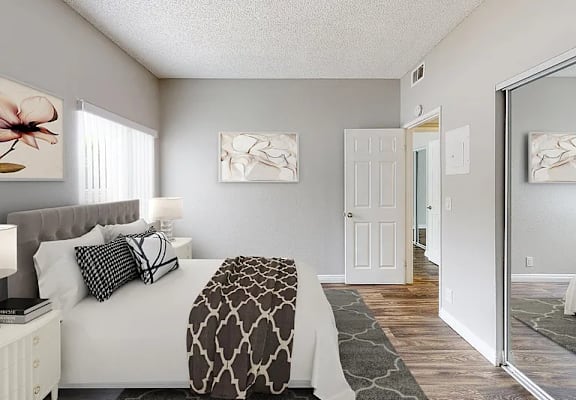 A bedroom with a bed, nightstand, and two framed pictures on the wall.