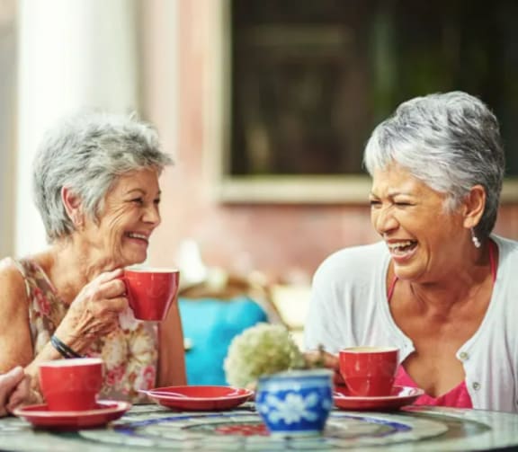 a couple of women sitting at a table with cups of coffee