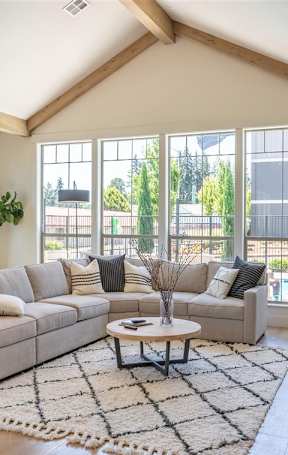 A modern living room with a fireplace and a large window overlooking a pool at St Helens Place Apartment Homes, Oregon
