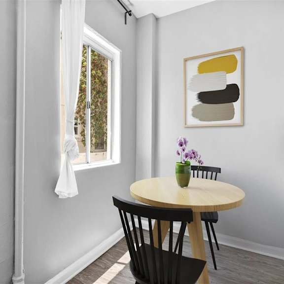 A dining room with a table, chairs, and a painting on the wall.