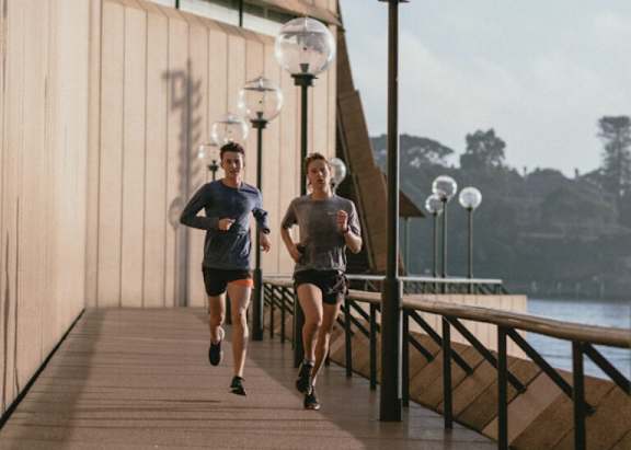 two men running on a bridge near a body of water