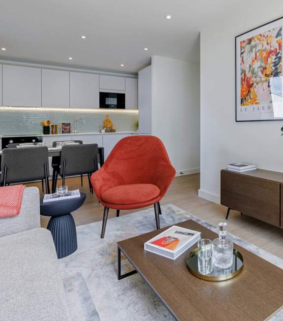 A red chair sits in a modern living room with a coffee table in front of it.