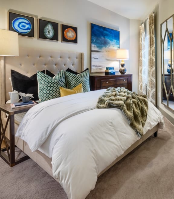 a bedroom with a large bed with white bedding and colorful pillows
