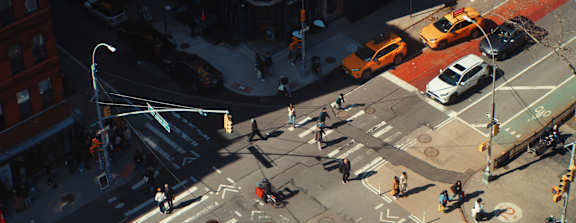 A busy city intersection with cars and pedestrians.