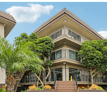A large house with a balcony and a tree in front.