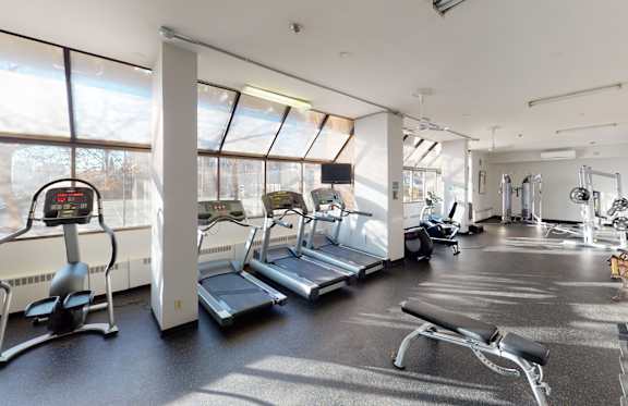 A gym with treadmills, elliptical machines, and other exercise equipment.