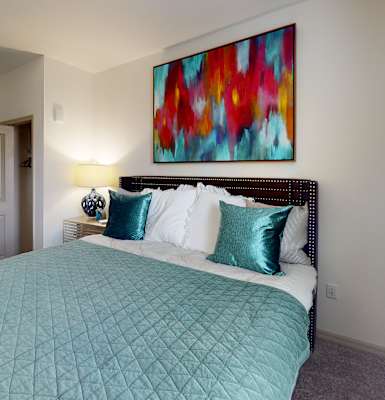 a bedroom with a large bed and a colorful painting on the wall at Integra 360 Apartments, Winter Springs, FL, 32708