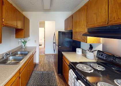 A kitchen with wooden cabinets and a black refrigerator.