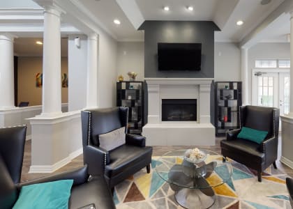 a living room with black leather chairs and a fireplace