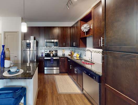 a kitchen with dark wood cabinets and stainless steel appliances at Integra 360 Apartments, Winter Springs, FL, 32708