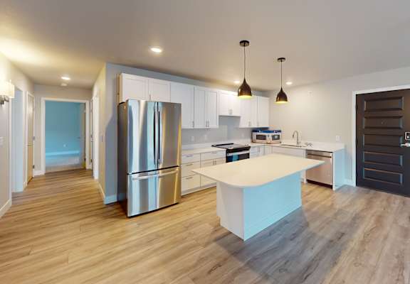 A modern kitchen with a refrigerator, sink, and cabinets.
