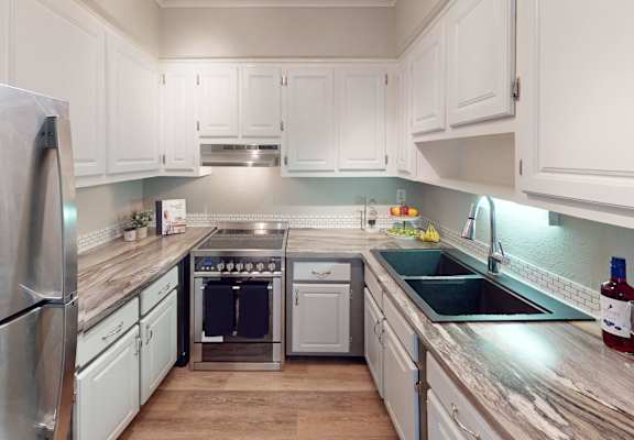 A kitchen with white cabinets and a stainless steel refrigerator.