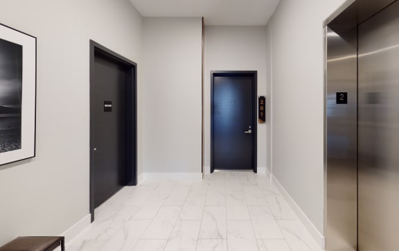 a hallway with three elevators and a black door