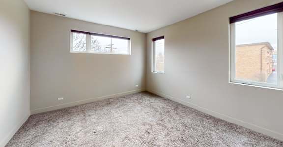 Empty room with carpeted floor and two windows.