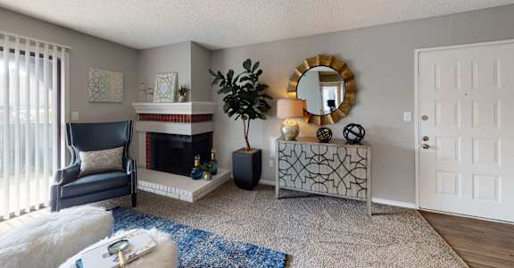 A living room with a fireplace, a chair, a mirror, and a plant.