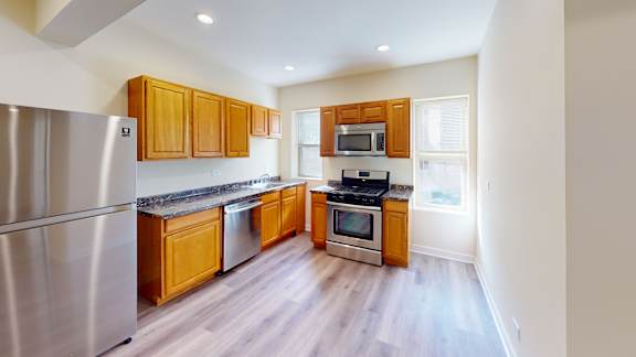 an empty kitchen with wood flooring and a large window