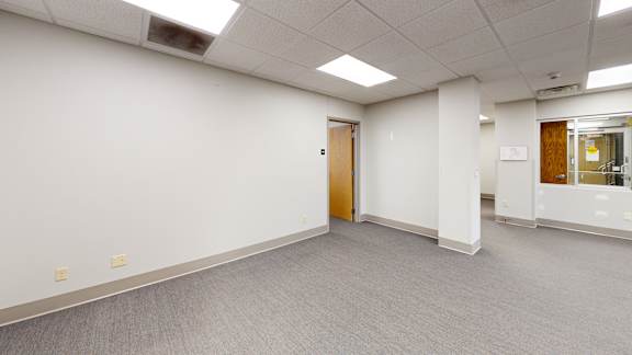 A room with a carpeted floor and a door on the left side.