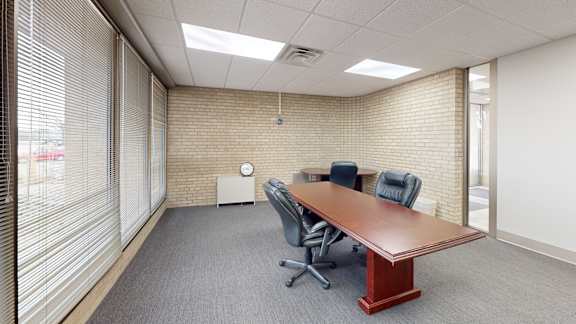 A conference room with a long table and two chairs.