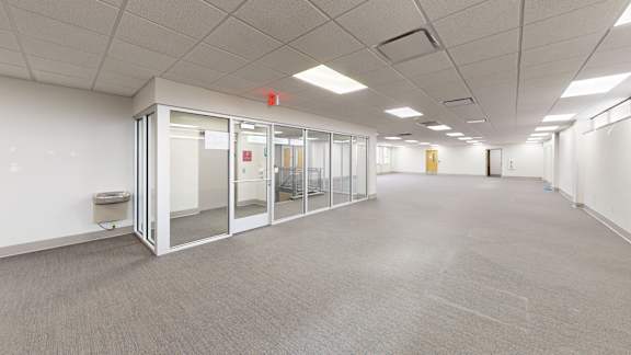 A long hallway with glass doors and a red exit sign.