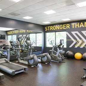 a workout room with cardio equipment and a sign stronger than you on the wall