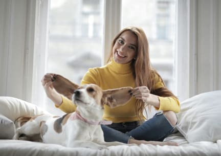 a woman sitting on a bed with a dog
