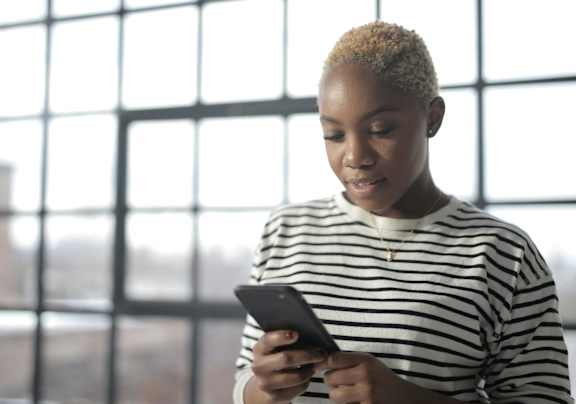 A person in a striped shirt is holding a smartphone.