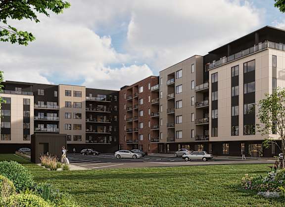 A modern apartment complex with a parking lot in front.