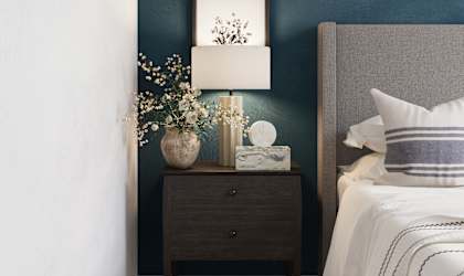 a bedroom with a bed and a night stand with a lamp and flowers