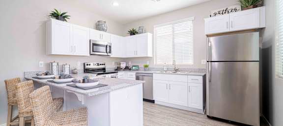A modern kitchen with a center island and stainless steel appliances at Vistoria At Country Place Apartments, Tolleson, AZ, 85353