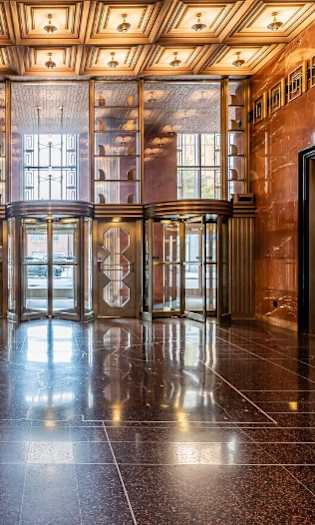 A hallway with marble floors and wooden ceiling with lighting fixtures.