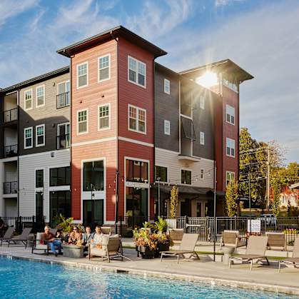 A group of people are sitting by a pool in front of a building.