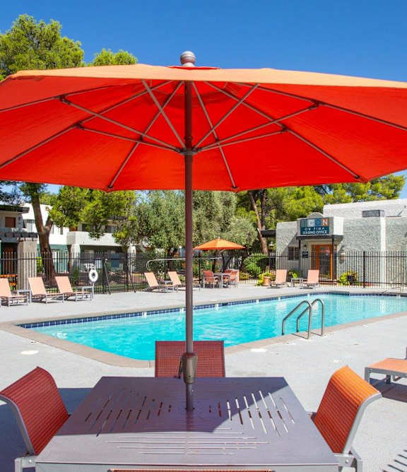 A pool with a table and chairs and an umbrella.