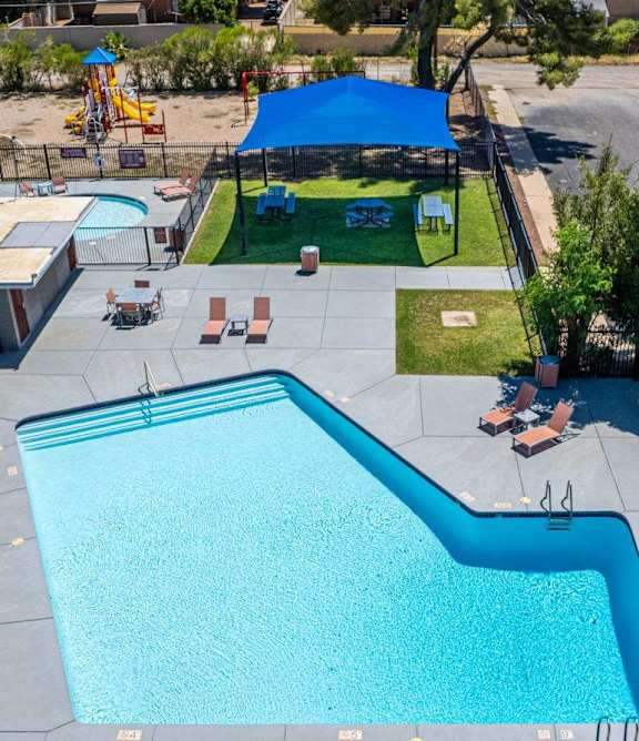 A large blue swimming pool with a slide and a playground.