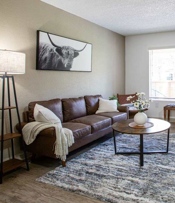 A brown leather couch with a white pillow and a white blanket is in the living room.
