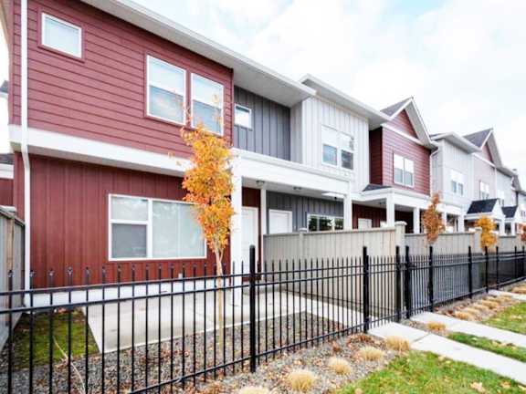 A row of houses with a black fence in front.