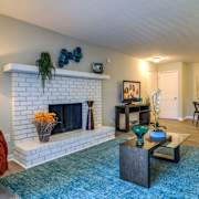 A living room with a fireplace and a blue rug.