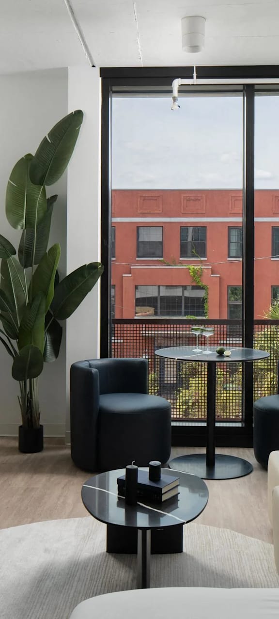 A living room with a large window and a view of a red building.