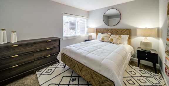 A bedroom with a large bed, a dresser, and a mirror on the wall.