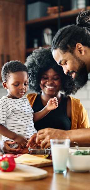 A family of three is preparing a meal together in a kitchen.