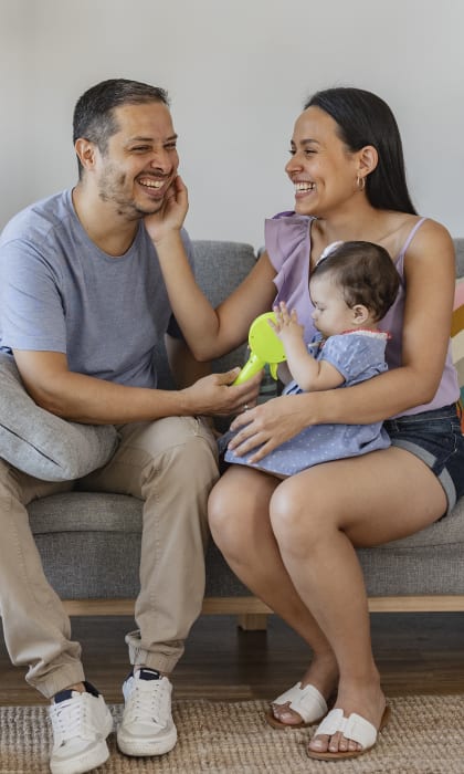 a man and woman sitting on a couch with a baby