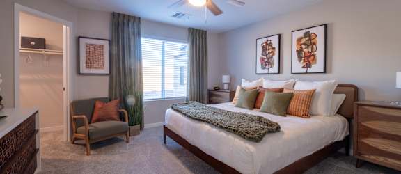 A bedroom with a bed, chair, and pictures on the wall.