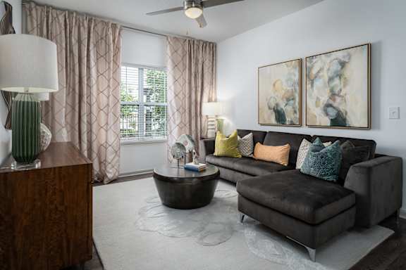 A bedroom with a large bed, a nightstand, and a window with white curtains.