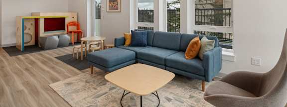 A living room with a blue couch and a wooden table.