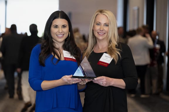 two women holding an award at a awards ceremony
