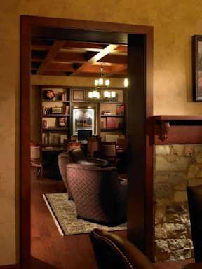 A brown leather chair sits in a room with a stone wall and a mirror.
