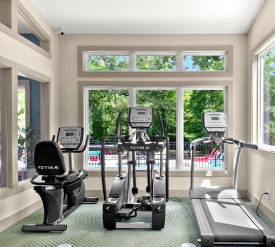 A gym with a treadmill, elliptical trainer and a stationary bike.