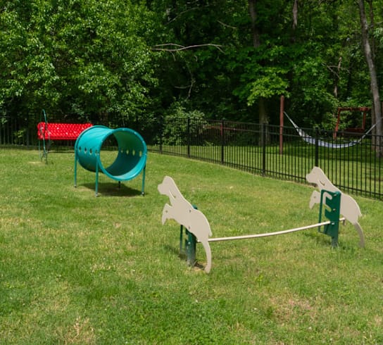 A playground with a slide, swings, and a seesaw.