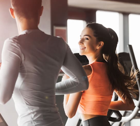 Two people are working out on treadmills in a gym.