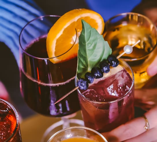 A close-up of people holding drinks with a focus on their hands and the drinks.