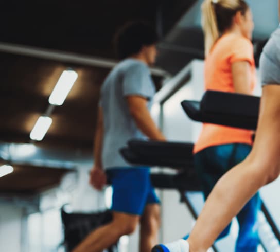 A woman is running on a treadmill in a gym.